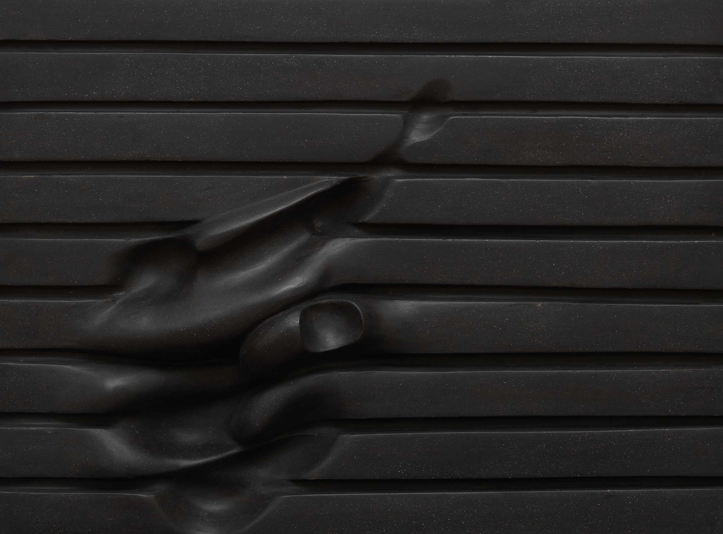 Die Abbildung zeigt das Werk Querfeld des Künstlers Hermann Frauenknecht aus dem Jahr 1982. Es besteht aus einer schwarzen Schaumstoffplatte mit horizontalen Rillen, in die durch Wärmeeinwirkung organisch anmutende Vertiefungen eingedrückt wurden. Die Fotoaufnahme stammt von Annette Kradisch.