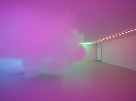 Die Aufnahme zeigt einen leeren Raum, in dem eine mit einer Nebelmaschine erzeugte Wolke schwebt. Durch an der Decke befestigte Beleuchtung wird die Wolke und Szenerie in blau-violett-rosanes Licht getaucht. Die Aufnahme stammt von Alistair Overbruck.