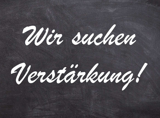 Die Abbildung zeigt vor dem Hintergrund einer typischen grauen Schultafel mit Kreidespuren den weißen Schriftzug "Wir suchen Verstärkung!". Die Grafik stammt von Thomas Ruppenstein.