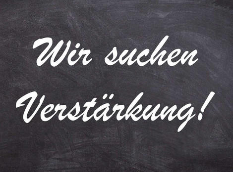 Die Abbildung zeigt vor dem Hintergrund einer typischen grauen Schultafel mit Kreidespuren den weißen Schriftzug "Wir suchen Verstärkung!". Die Grafik stammt von Thomas Ruppenstein.