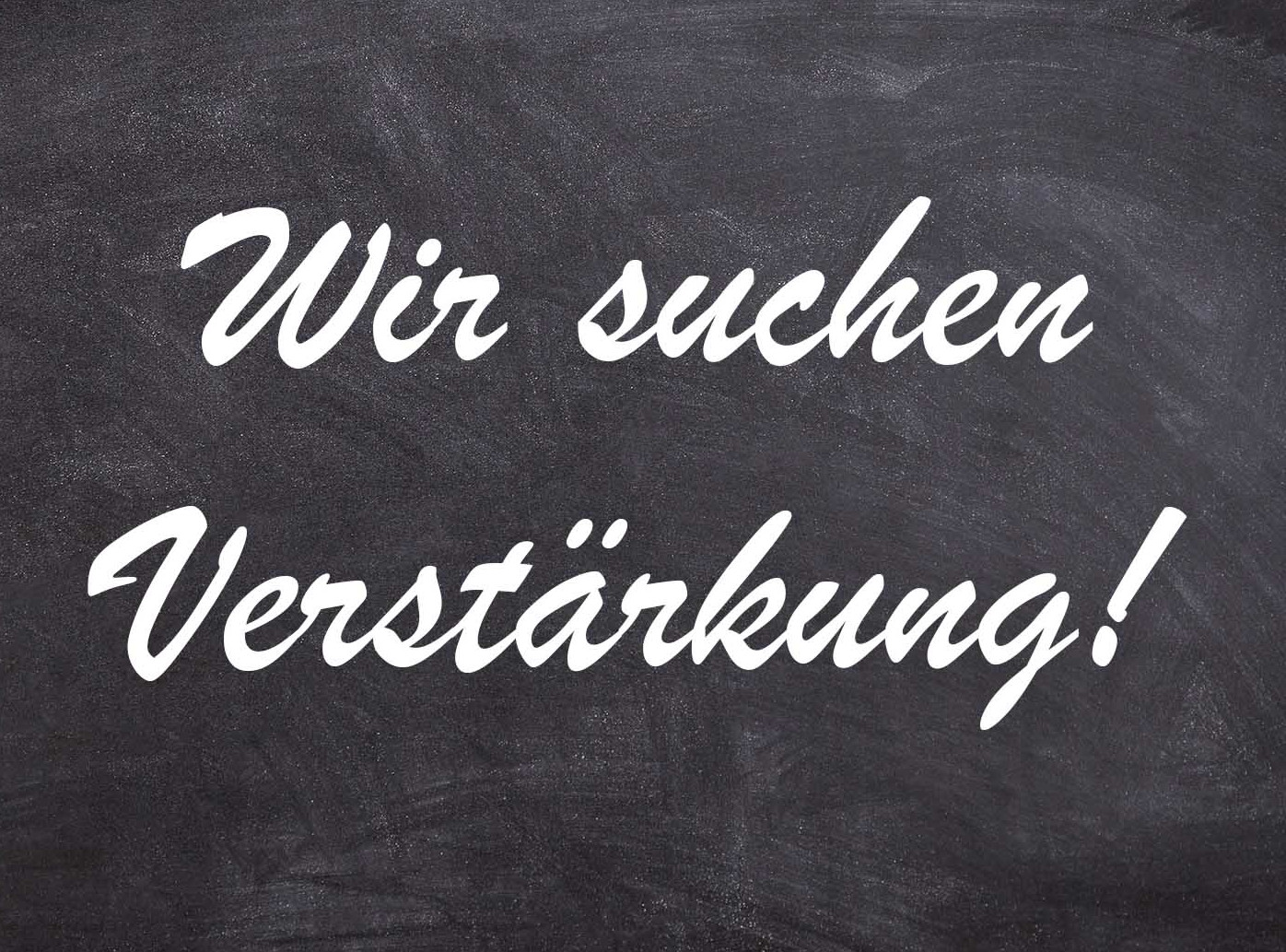 Die Abbildung zeigt vor dem Hintergrund einer typischen grauen Schultafel mit Kreidespuren den weißen Schriftzug "Wir suchen Verstärkung!". Die Grafik stammt von Thomas Ruppenstein.