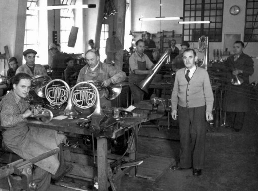 Die Abbildung zeigt die Werkstatt der Firma Wenzel Meinl für Musikinstrumentenbau in Geretsried im Jahr 1952. Die Fotoaufnahme stammt von Gerhard A, Meinl.