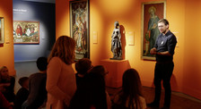 Die Abbildung zeigt eine Gruppe von Schüler*innen beim Besuch einer Ausstellung im Germanischen Nationalmuseum. Ein Mann steht vor einem Gemälde und erläutert es. Die Schüler*innen sitzen im Halbkreis um ihn und das Kunstwerk herum und hören zu. Die Fotoaufnahme stammt von Thomas Ruppenstein. mittelschulcurriculum.jpg