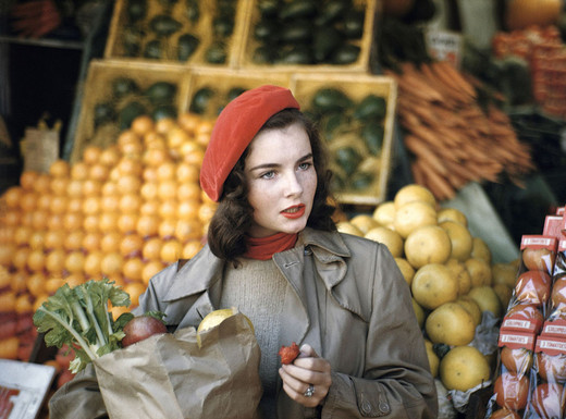 Die Abbildung zeigt eine von Ruth Orkin angefertigte Fotoaufnahme. Sie zeigt eine Frau, Geraldine Dent, beim Einkauf von Obst und Gemüse in New York City, 1949.