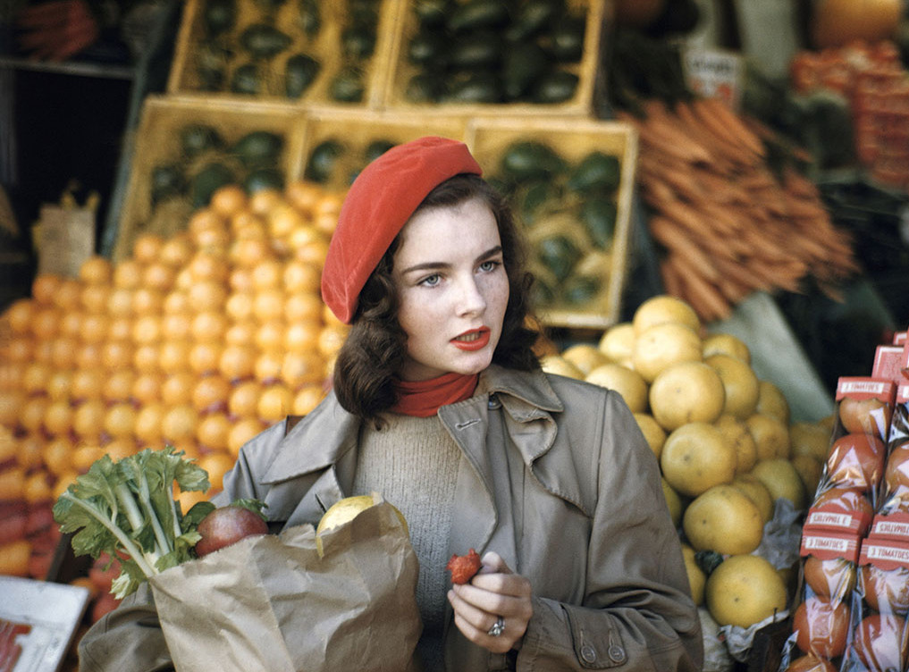 Die Abbildung zeigt eine von Ruth Orkin angefertigte Fotoaufnahme. Sie zeigt eine Frau, Geraldine Dent, beim Einkauf von Obst und Gemüse in New York City, 1949.