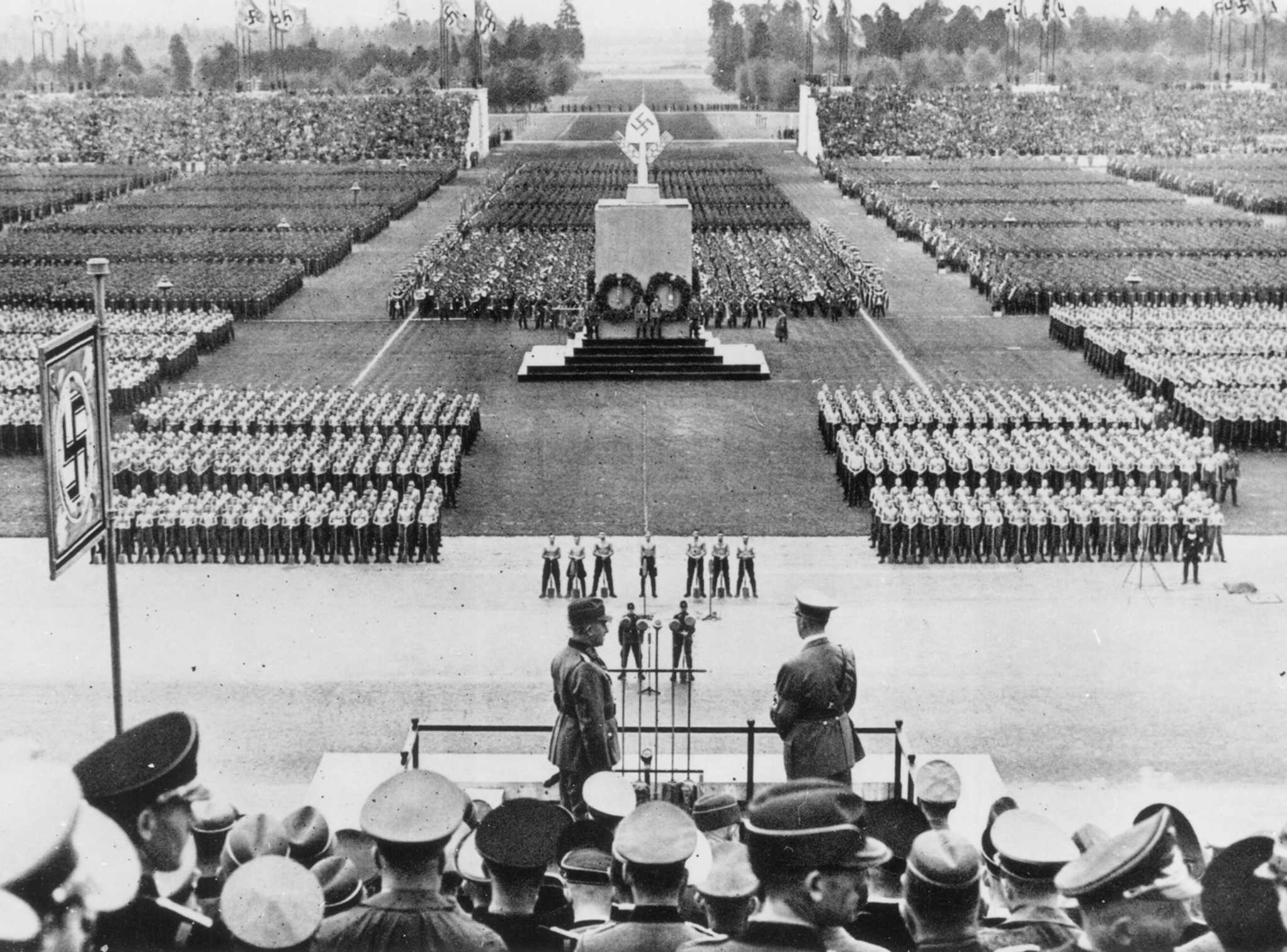 Die Abbildung zeigt eine historische Fotoaufnahme vom Appell des Reichsarbeitsdienstes auf dem Zeppelinfeld vor Adolf Hitler und Konstantin Hierl im Jahr 1938. Die Fotoaufnahme stammt vom Dokumentationszentrum Reichsparteitagsgelände und trägt die Archivnummer 397.06.