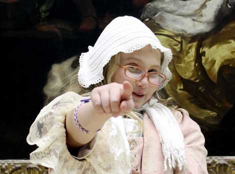 Die Abbildung zeigt eine kostümierte Jugendliche, die vor einem Gemälde im Germanischen Nationalmuseum steht und mit dem Finger auf die Betrachtenden zeigt. Die Aufnahme stammt von Thomas Ruppenstein.