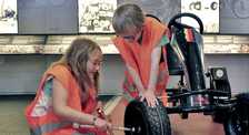 Zwei Kinder beim Reifenwechseln eines Gokarts im Museum Industriekultur | Fotoaufnahme von Thomas Ruppenstein boxenstopp.jpg