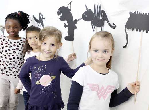 Die Abbildung zeigt Kinder beim Schattenspiel mit selbstgestalteten Drachen aus schwarzem Karton. Die Fotoaufnahme stammt von Giulia Iannicelli (Stadt Nürnberg).