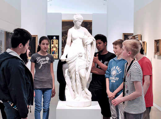 Die Abbildung zeigt Jugendliche im Gespräch um eine an antike Vorbilder angelehnte Skulptur einer jungen Frau. Die Fotoaufnahme stammt von Thomas Ruppenstein.