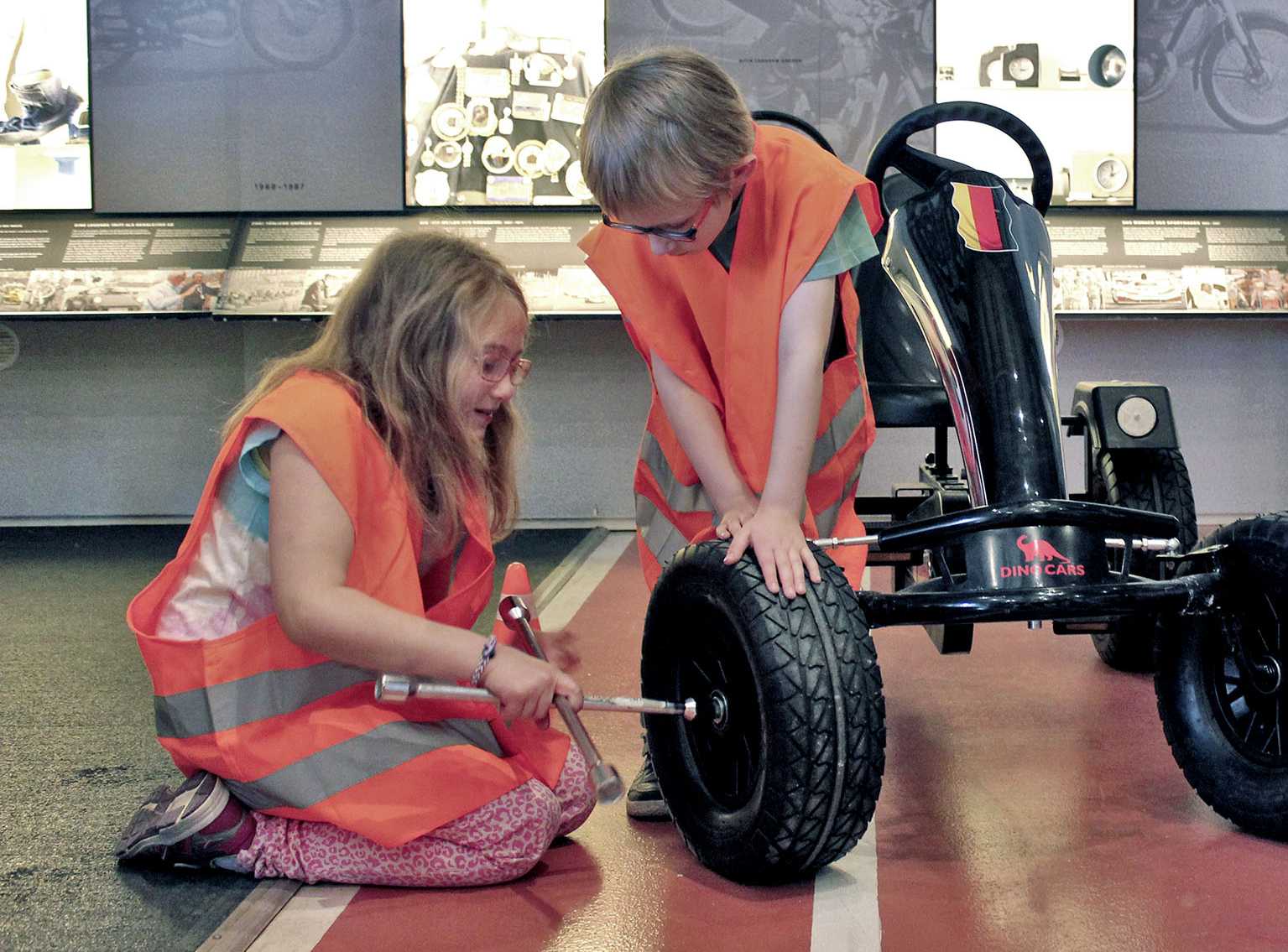 Zwei Kinder beim Reifenwechseln eines Gokarts im Museum Industriekultur | Fotoaufnahme von Thomas Ruppenstein