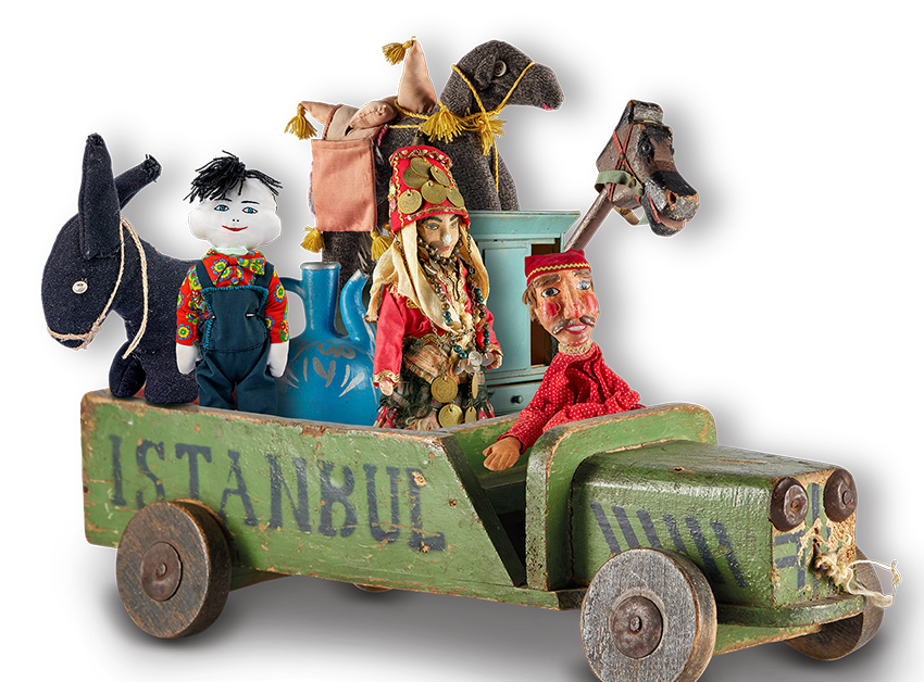 Die Abbildung zeigt eine Objektcollage, bestehend aus verschiedenen Spielzeugfiguren, die in einem Holzspielzeuglastwagen sitzen, auf dem Istanbul steht. Die Fotoaufnahme stammt vom Spielzeugmuseum. 
