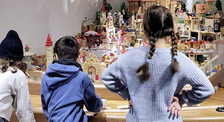Die Abbildung zeigt drei Kinder im Grundschulalter, die im Spielzeugmuseum das Stadtmodell aus Spielzeug betrachten. Die Kinder stehen mit dem Rücken zur Kamera und schauen auf das Modell. Die Aufnahme stammt von Thomas Ruppenstein. museumscurriculum_grundschulen.jpg
