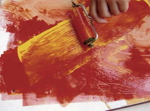 Die Abbildung zeigt eine Hand mit Farbwalze, die rote Farbe für den Hochdruck aufnimmt. Die Fotoaufnahme stammt von Lioba Pilgram.