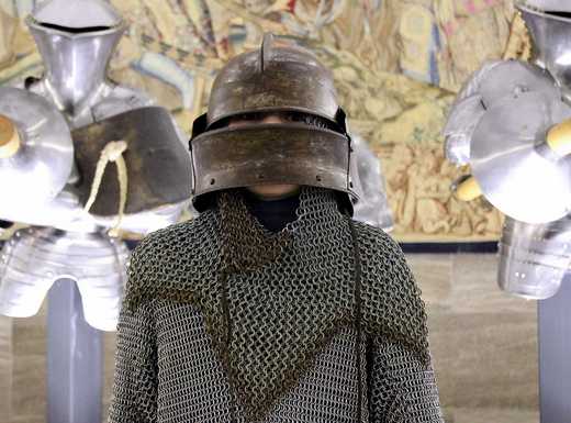 Die Abbildung zeigt einen Jungen in der Waffen- und Rüstungssammlung des Germansichen Nationalmuseums. Er trägt einen frühneuzeitlichen Helm mit Visier sowie Kettenhemd und Kettenhaube. Die Fotoaufnahme stamm von Thomas Ruppenstein.