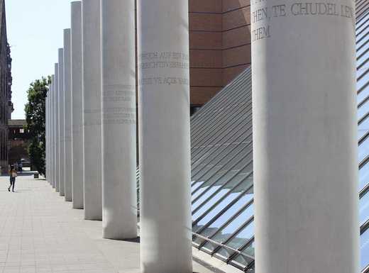 Die Abbildung zeigt die Straße der Menschenrechte. Dominant sind die großen Betonsäulen, auf denen die einzelnen Rechte als Inschrift zu erkennen sind. Die Fotoaufnahme stammt von Thomas Ruppenstein.