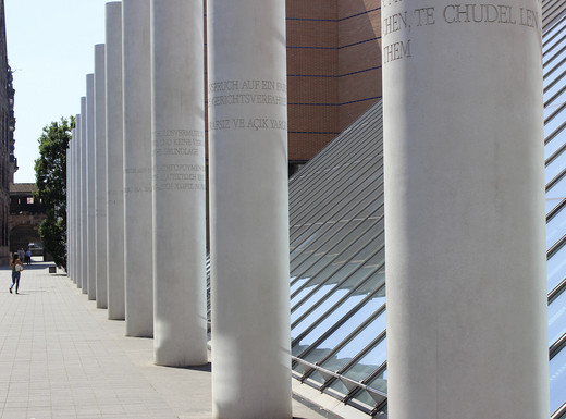Blick in die „Straße der Menschenrechte“ | Fotoaufnahme von Thomas Ruppenstein Die Abbildung zeigt die Straße der Menschenrechte. Dominant sind die großen Betonsäulen, auf denen die einzelnen Rechte als Inschrift zu erkennen sind. Die Fotoaufnahme stammt von Thomas Ruppenstein.